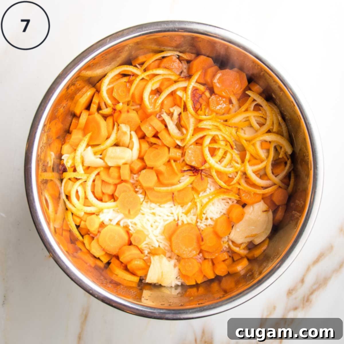 The Instant Pot insert, now revealing perfectly cooked, fluffy rice infused with colorful veggies, spices, and fragrant orange peels after the pressure release.