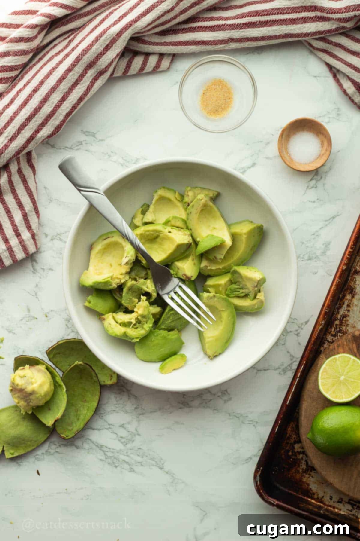 Peeled avocados in a bowl with a fork, ready for mashing.