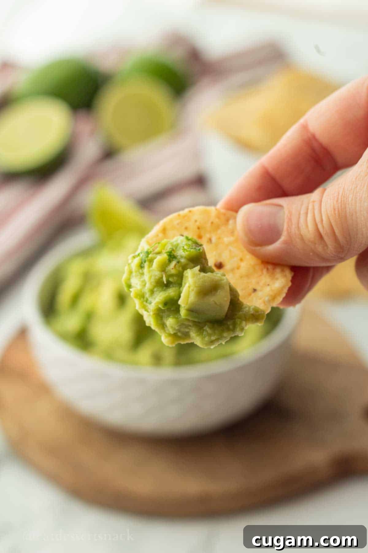 A tortilla chip scooping a generous portion of homemade guacamole from a bowl.