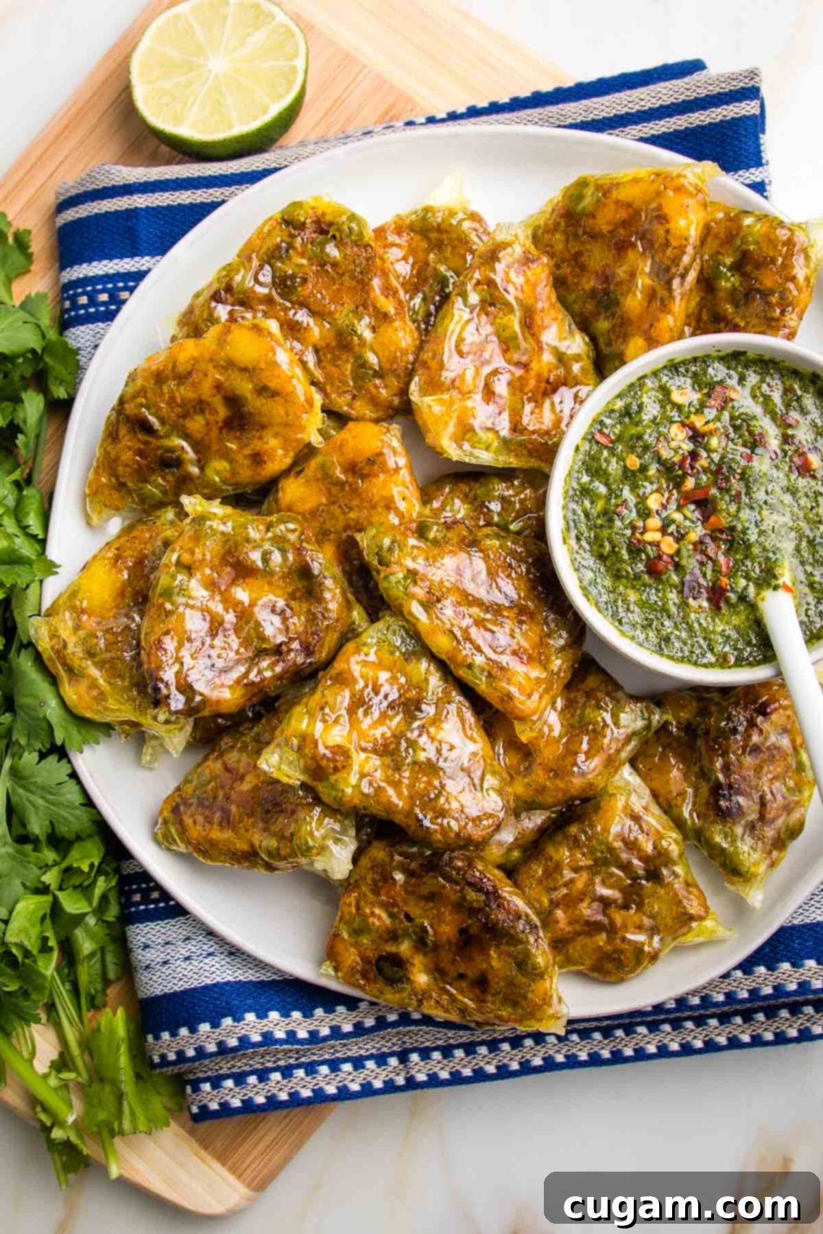 Plate of baked samosas with a small dish of green chutney.
