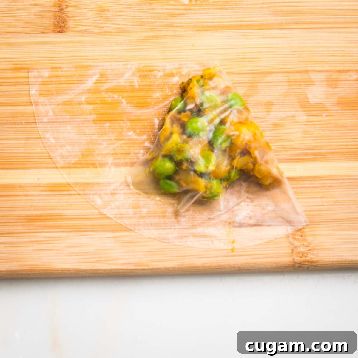 Half moon of wet rice paper, with a scoop of potato samosa filling, with one side folded over.