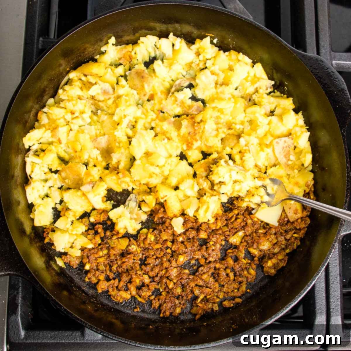 Cast iron skillet half filled with onion/garlic/spice mixture and the other half has diced boiled potatoes
