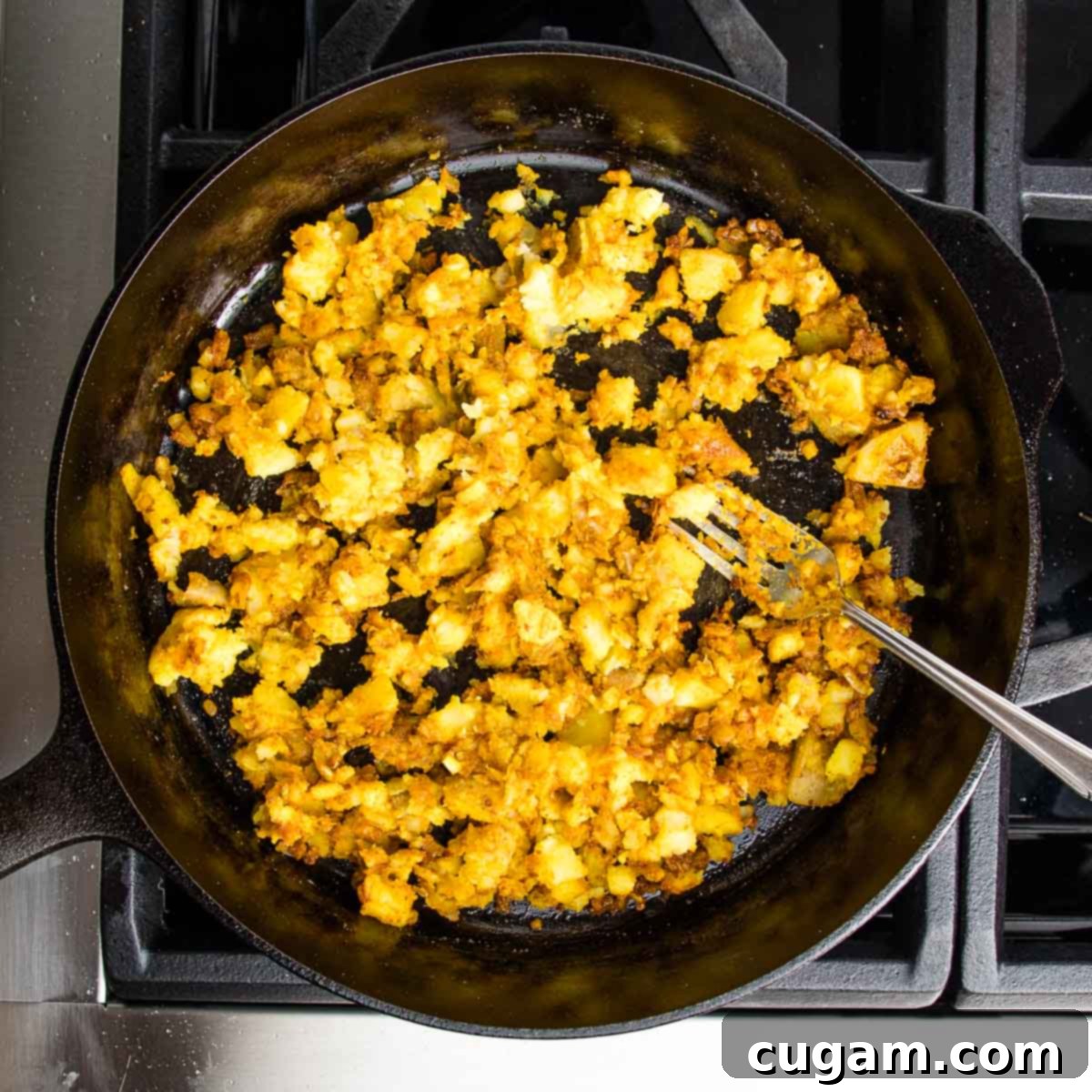Cast iron skillet filled with potatoes, onions, garlic and spices that have been sauteed.