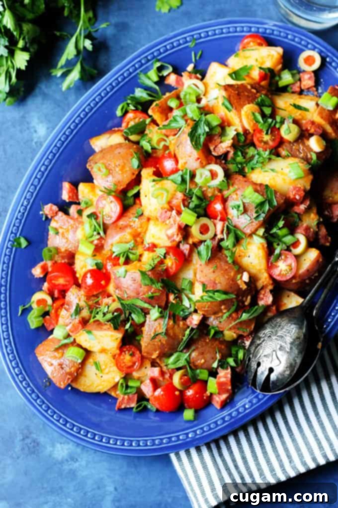 Smoky Spanish Potato Salad without mayo on a blue serving platter with serving spoon on a side