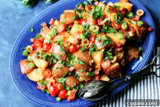 Horizontal photo of Spanish Potato Salad with Smoked Paprika Dressing on a blue serving plate with spoon