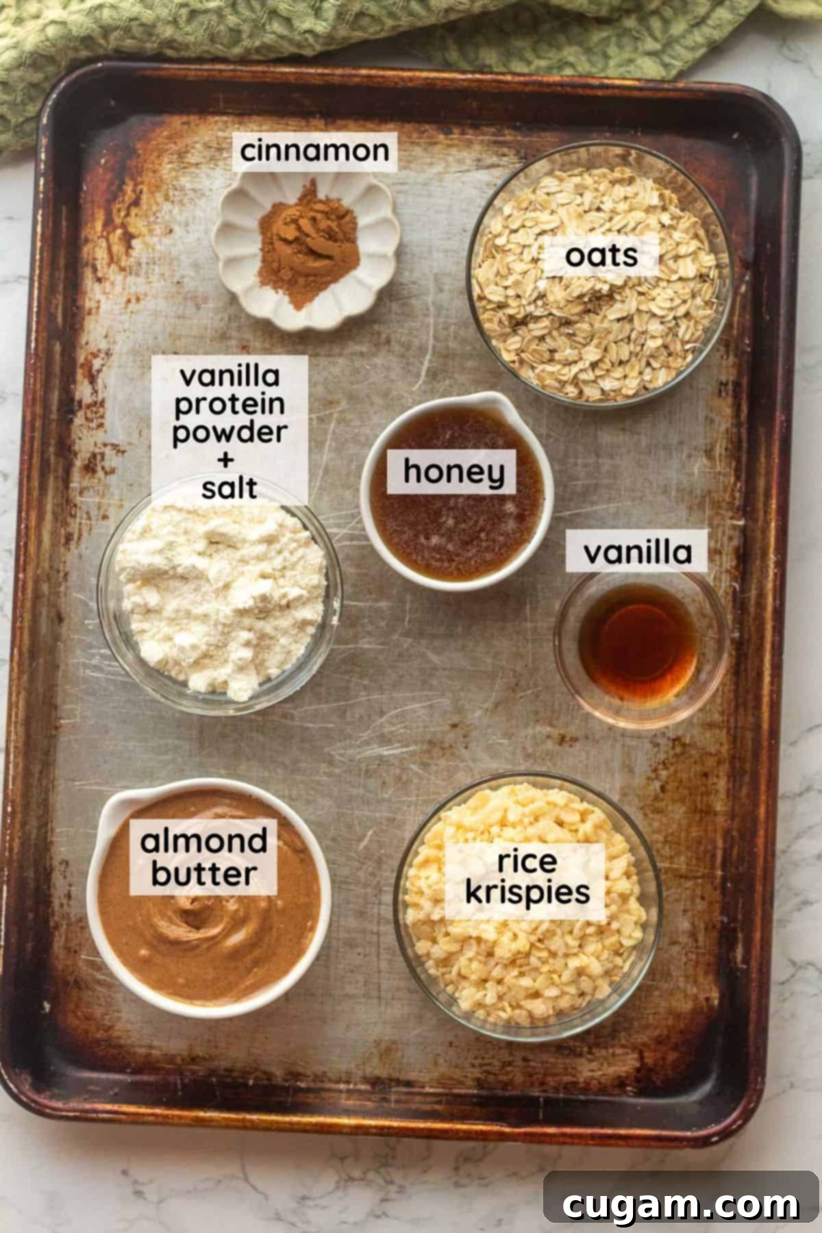 Labeled ingredients for protein cinnamon balls on metal baking sheet.