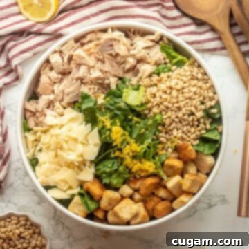 Lemon zest on chicken caesar salad in bowl with wooden spoons.