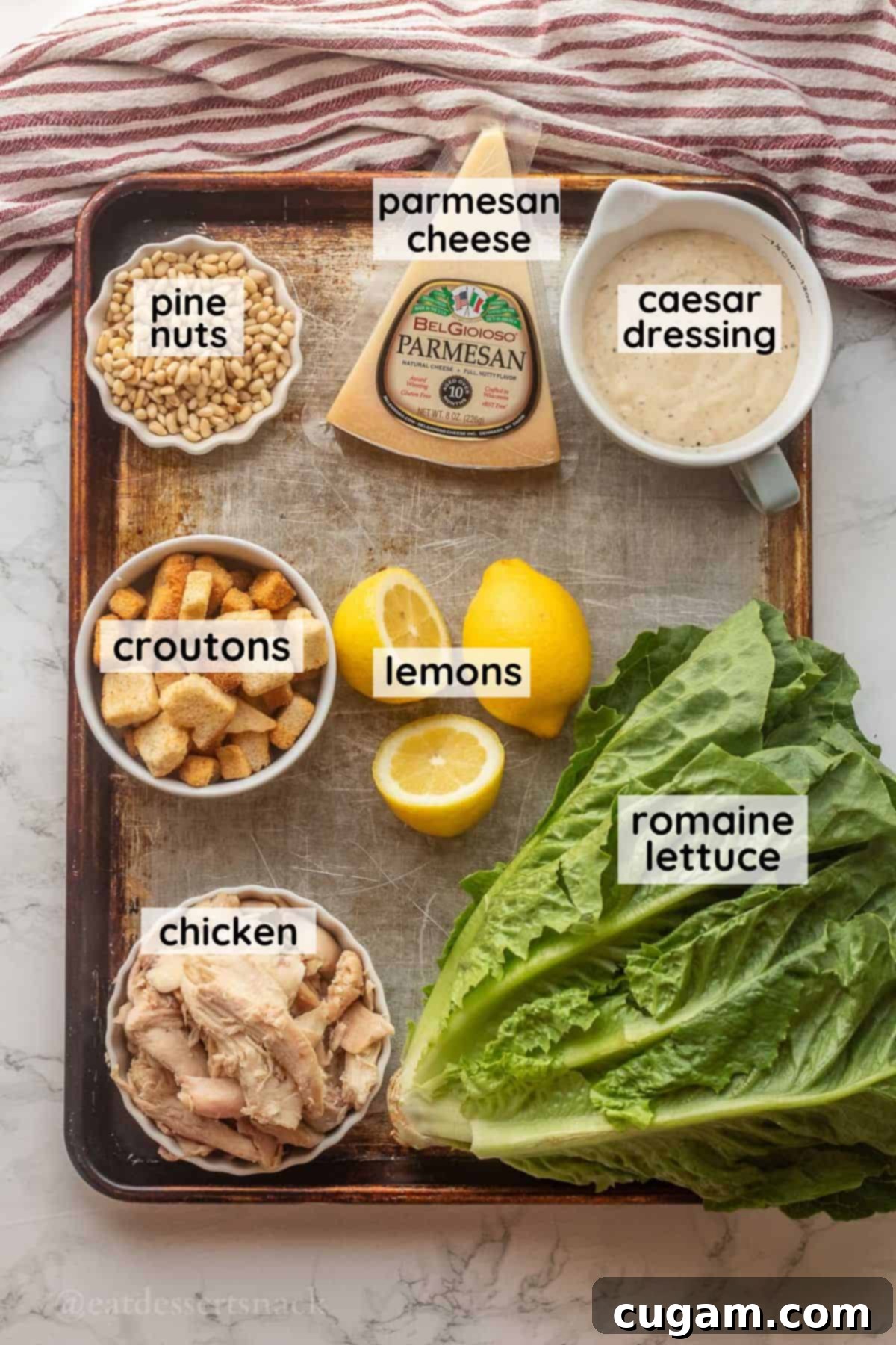 Labeled ingredients for lemon chicken caesar salad on metal baking sheet.