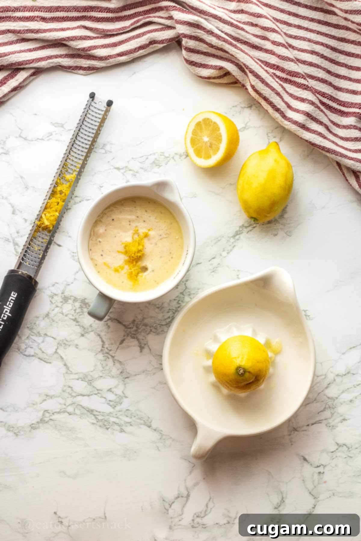 Lemon zest and juice in bowl with zester on marble countertop.