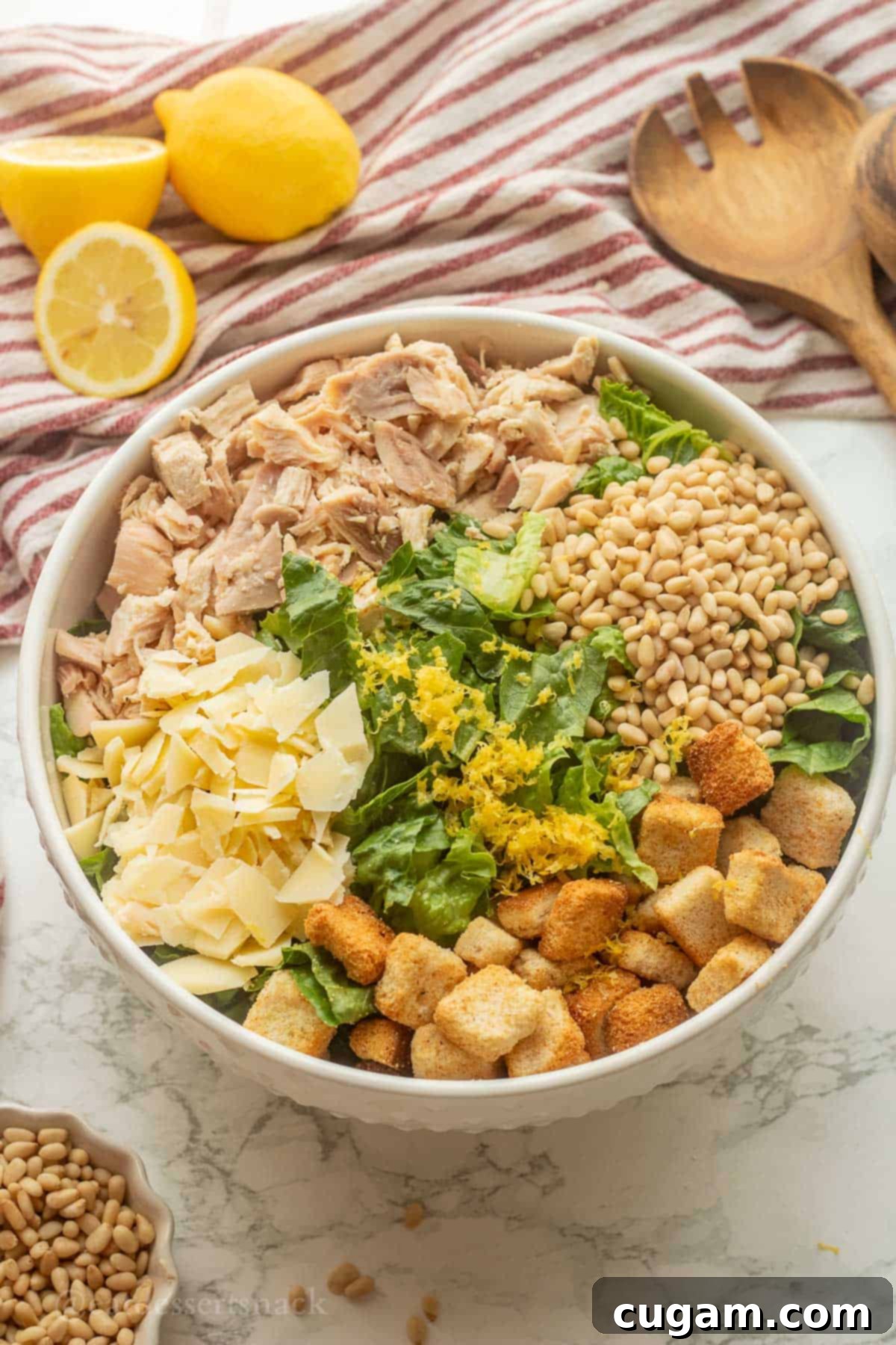 Lemon zest on chicken caesar salad in bowl.