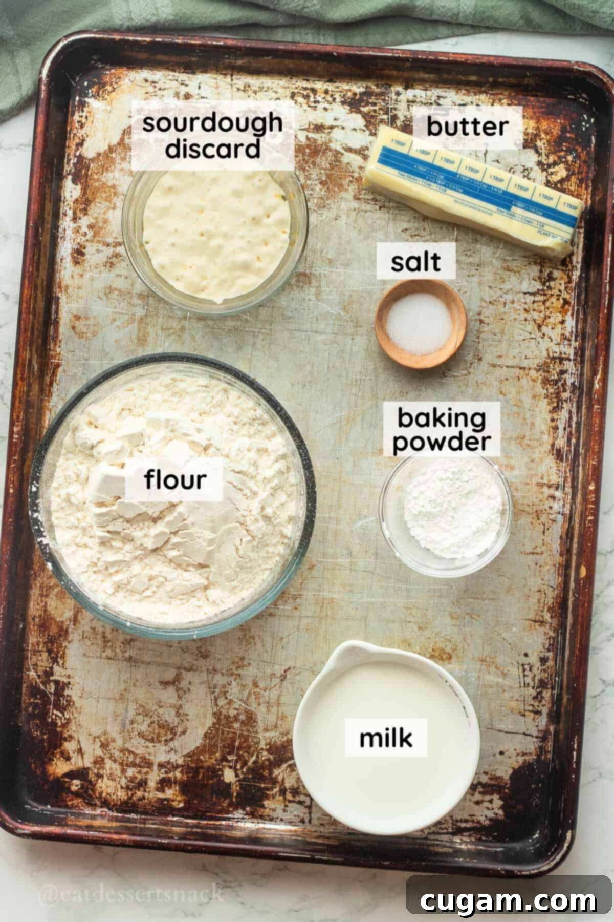 Flaky Sourdough Discard Biscuits 3 Labeled ingredients in dishes for sourdough biscuits on metal baking sheet.