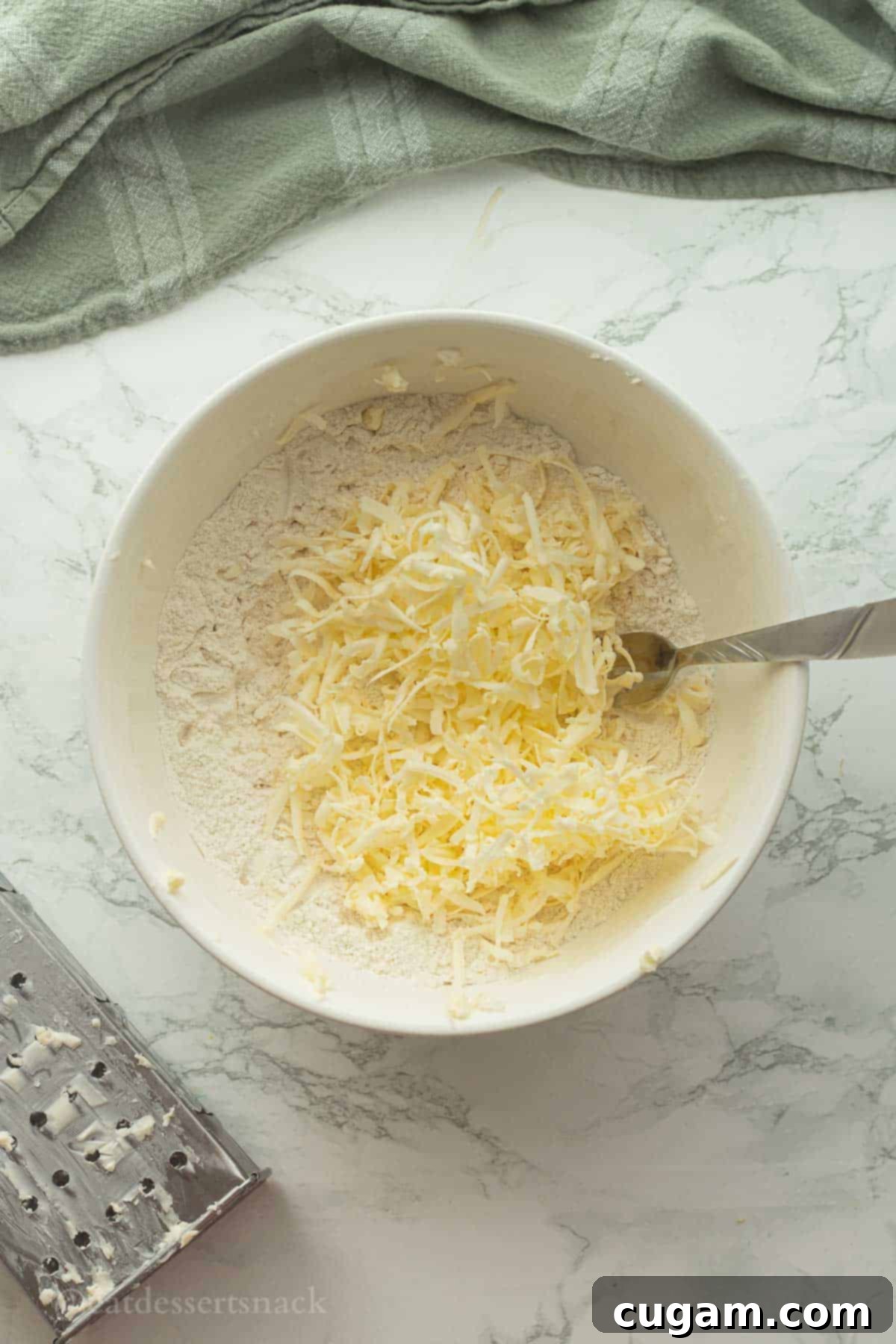 Flaky Sourdough Discard Biscuits 5 Grated butter in bowl of flour with fork.