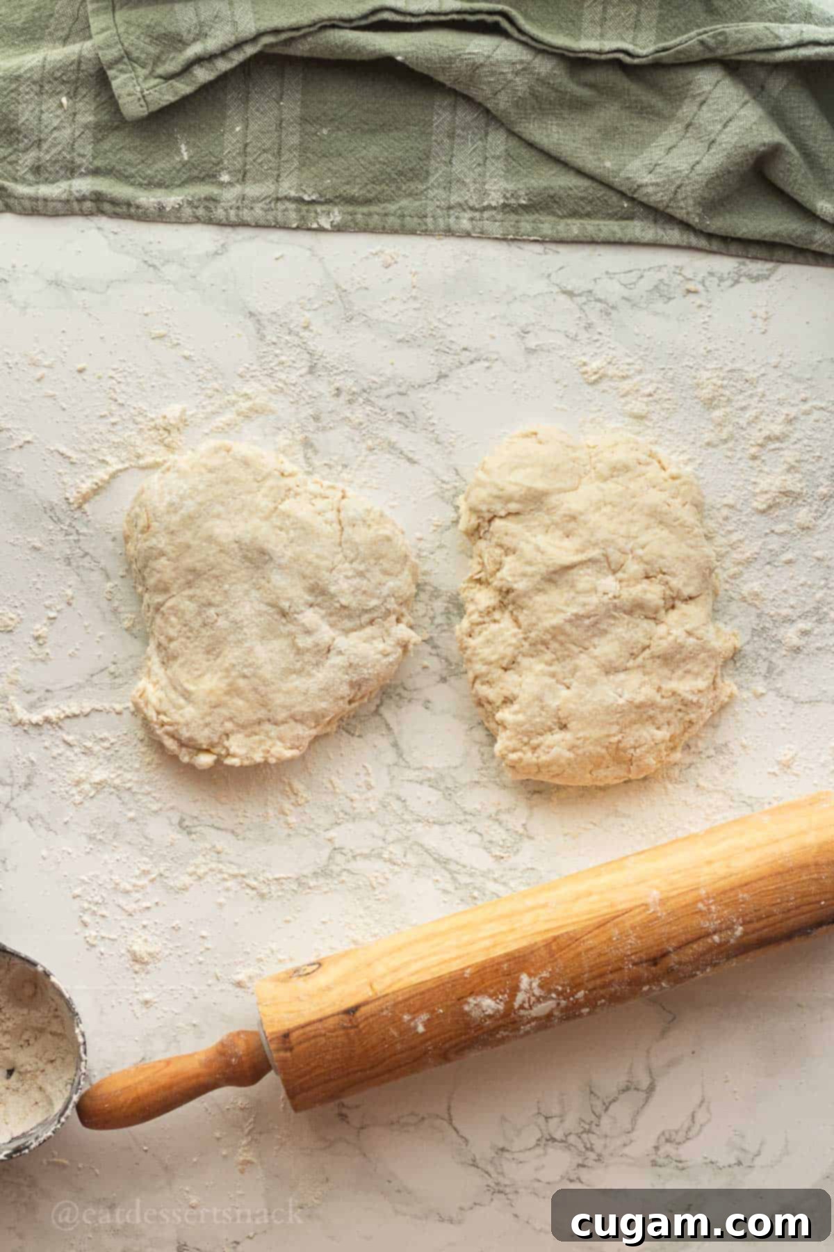Flaky Sourdough Discard Biscuits 7 2 sections of biscuit dough on marble with flour.