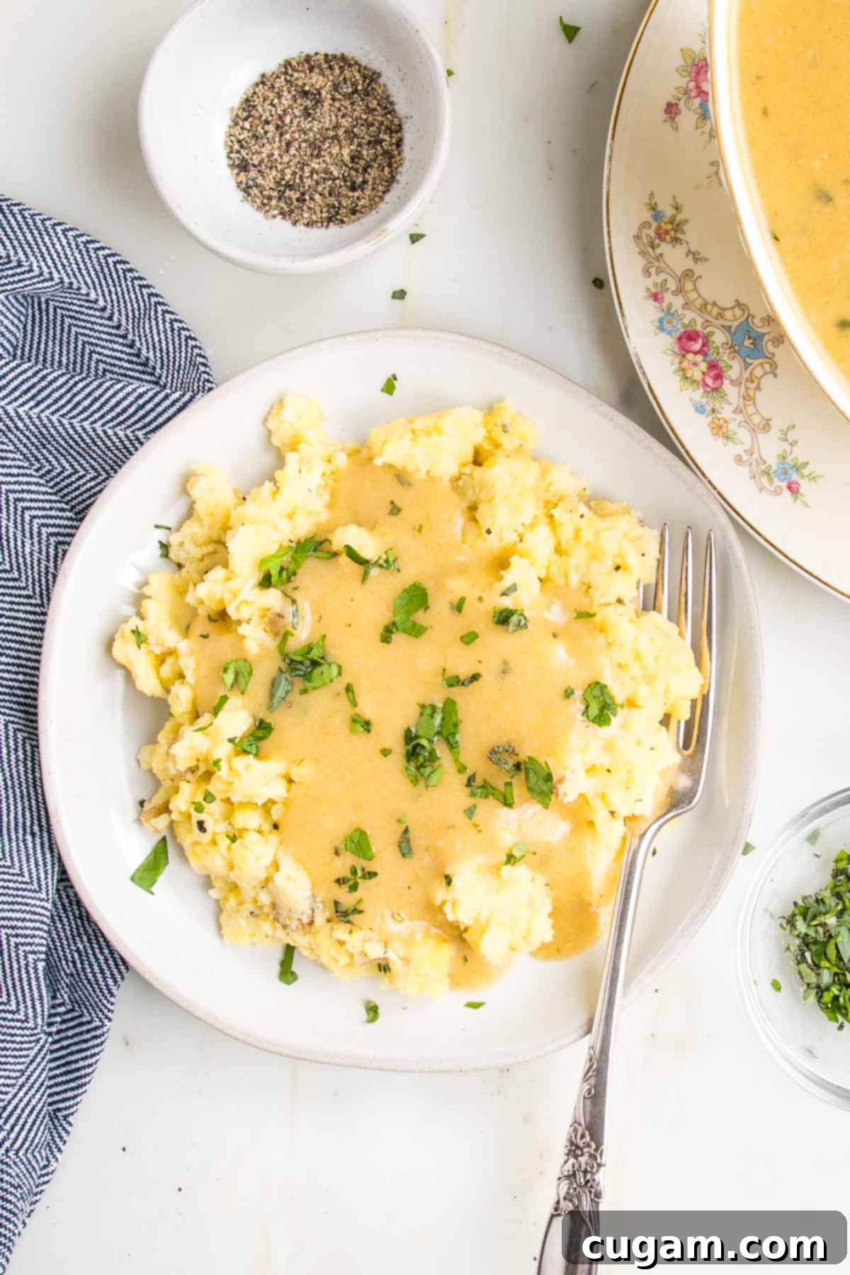 Plate full of mashed potatoes covered in vegan gravy and sprinkled with fresh herbs. 