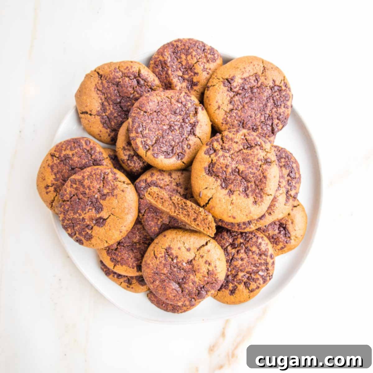 Irresistibly Chewy Vegan Ginger Gems 4 Ginger crinkle cookies, topped with chocolate. One cookie is broken open to see the chewy center.