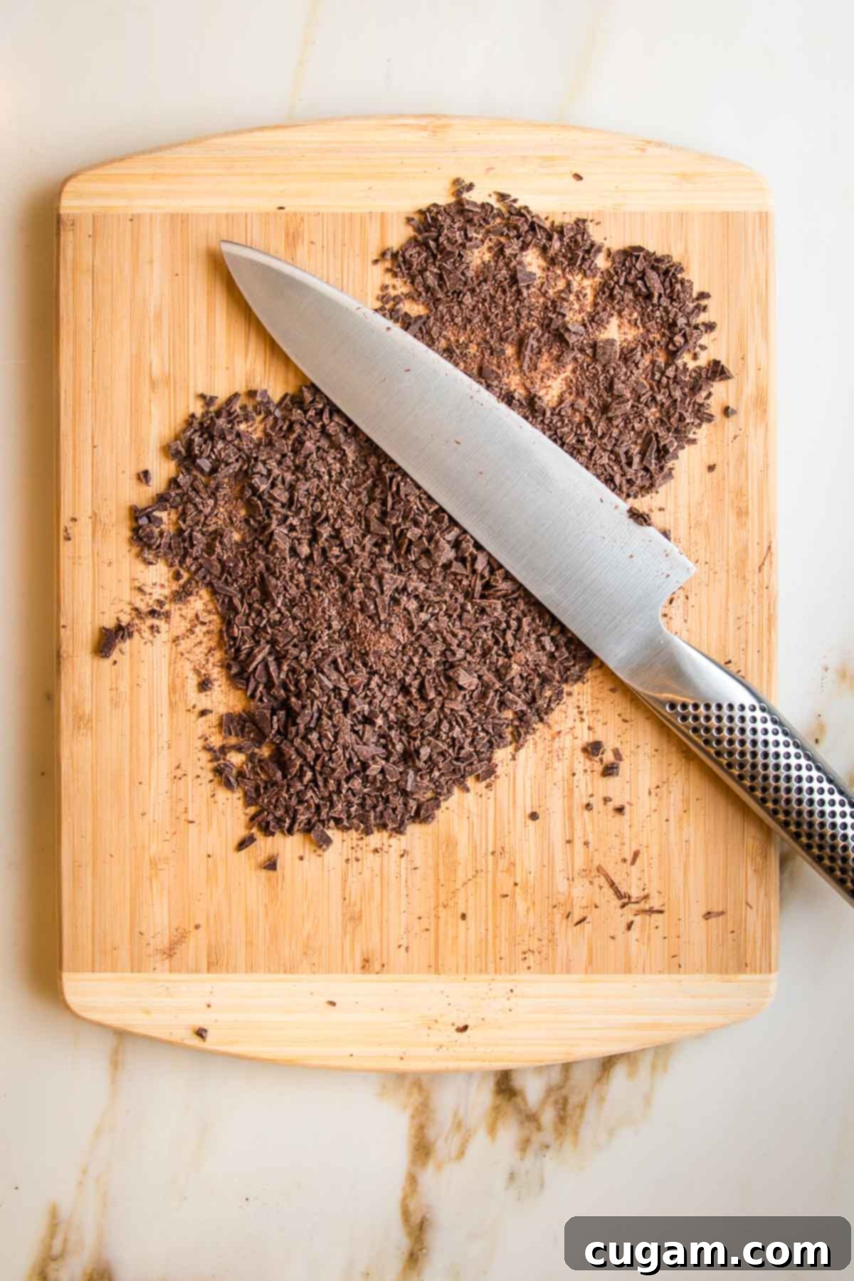 Irresistibly Chewy Vegan Ginger Gems 5 Dark chocolate chopped finely on a wooden board with a chef's knife.
