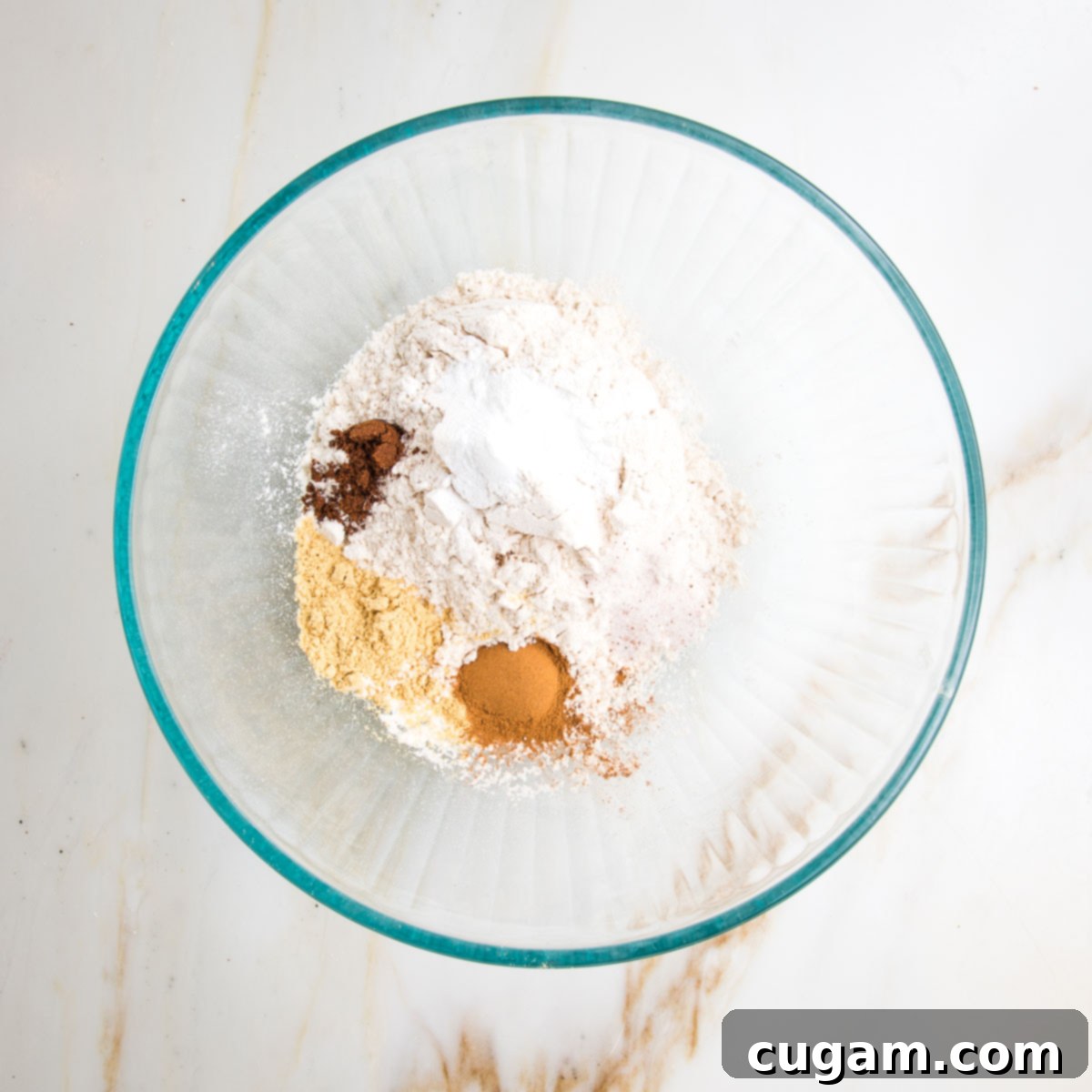 Irresistibly Chewy Vegan Ginger Gems 6 Large glass bowl with flour, baking soda, baking powder, cinnamon, all spice and ground cinger.