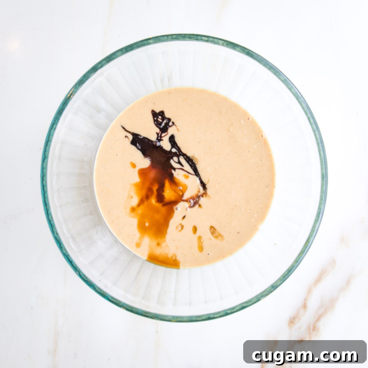 Irresistibly Chewy Vegan Ginger Gems 7 Glass mixing bowl with tahini and a swirl of molasses and some maple syrup. Various degrees of the color tan, amber and brown.