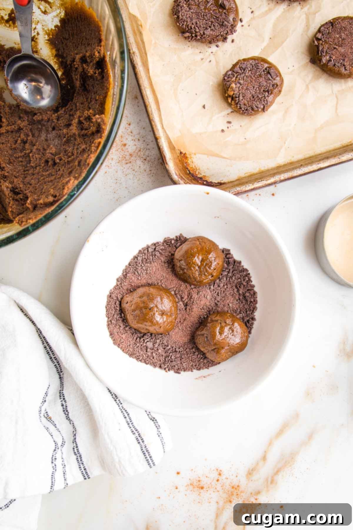 Irresistibly Chewy Vegan Ginger Gems 10 Finely chopped dark chocolate and three balls of cookie dough in a bowl. Cookie dough in a glass bowl and a baking tray collecting finished cookies.