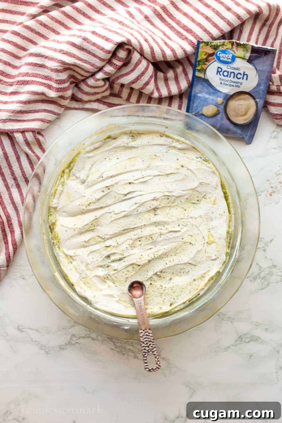 Spooky Spiderweb Taco Dip 6 Creamy sour cream mixed with ranch seasoning, forming the next layer in the pie dish for the layered dip.