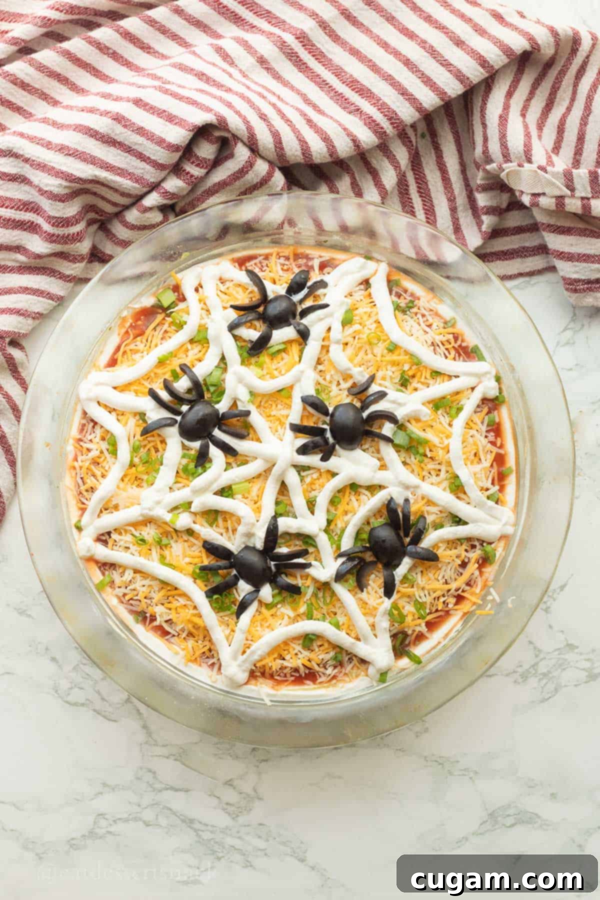 Spooky Spiderweb Taco Dip 9 A festive 5-layer bean dip with a charming spiderweb and olive spiders, ready to be served from a pie dish.