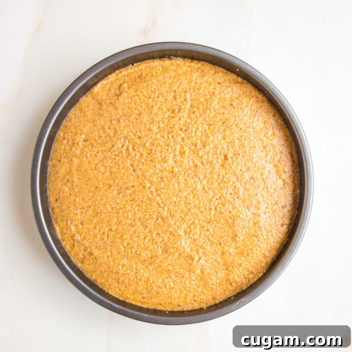 A round cake pan, perfectly lined, filled with the smooth pumpkin cake batter, ready for baking.