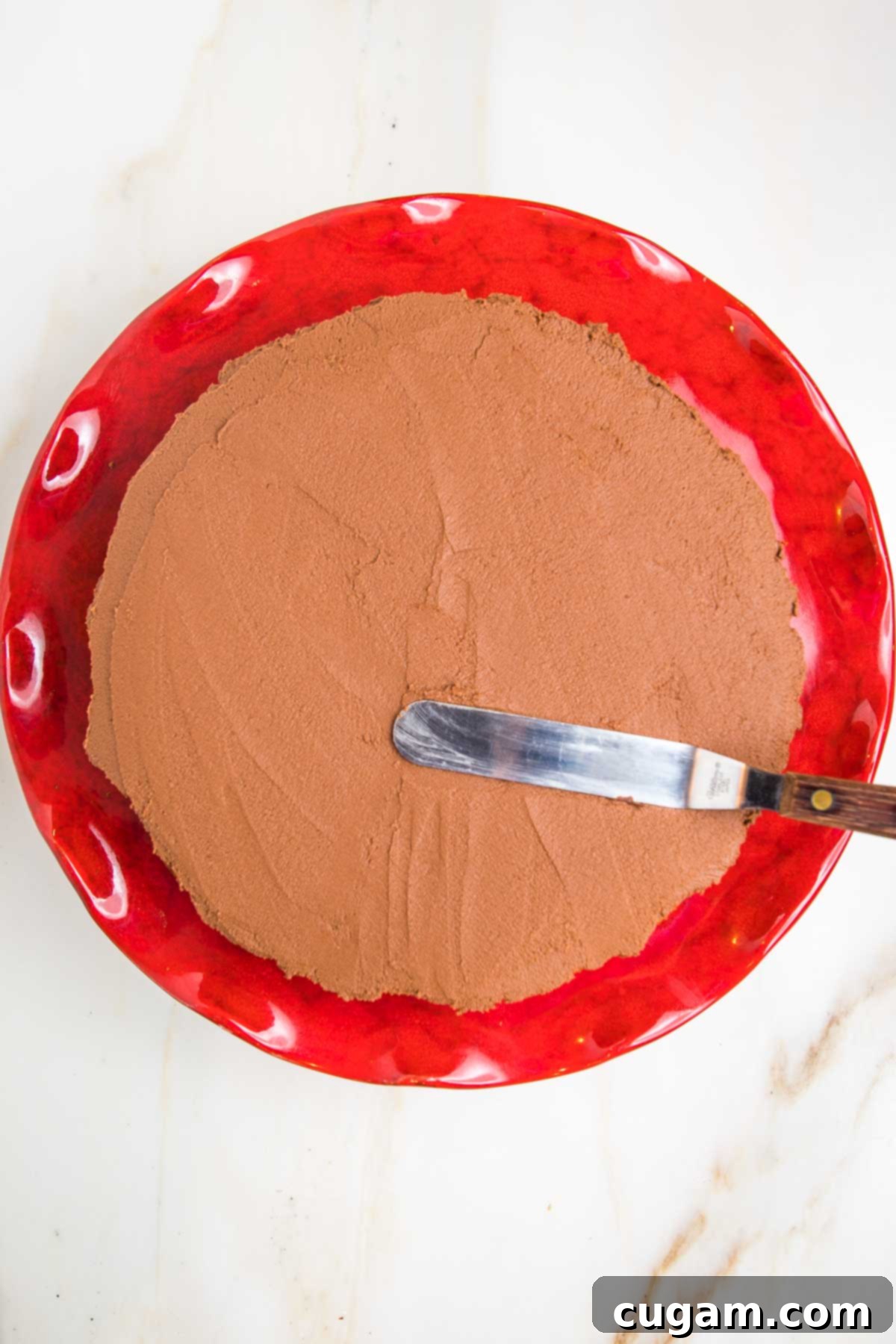 Thick, creamy vegan chocolate frosting meticulously spread over the entire top surface of a perfectly baked pumpkin cake, ready for decoration.