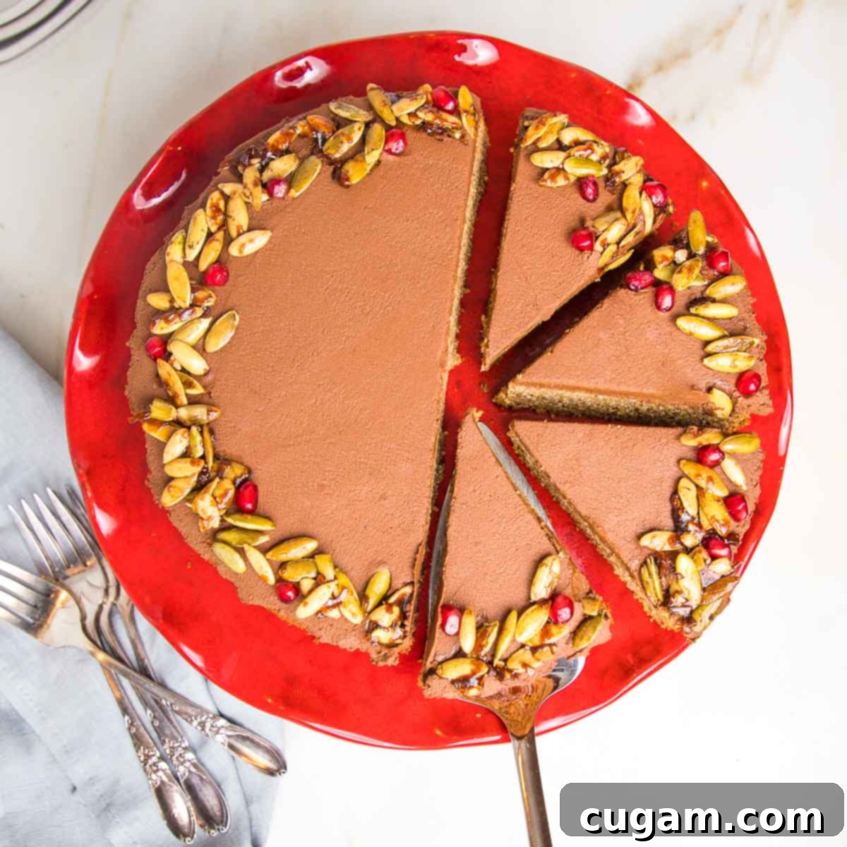 A frosted chocolate cake, elegantly adorned with candied nuts, with a few slices already cut, revealing its moist interior.