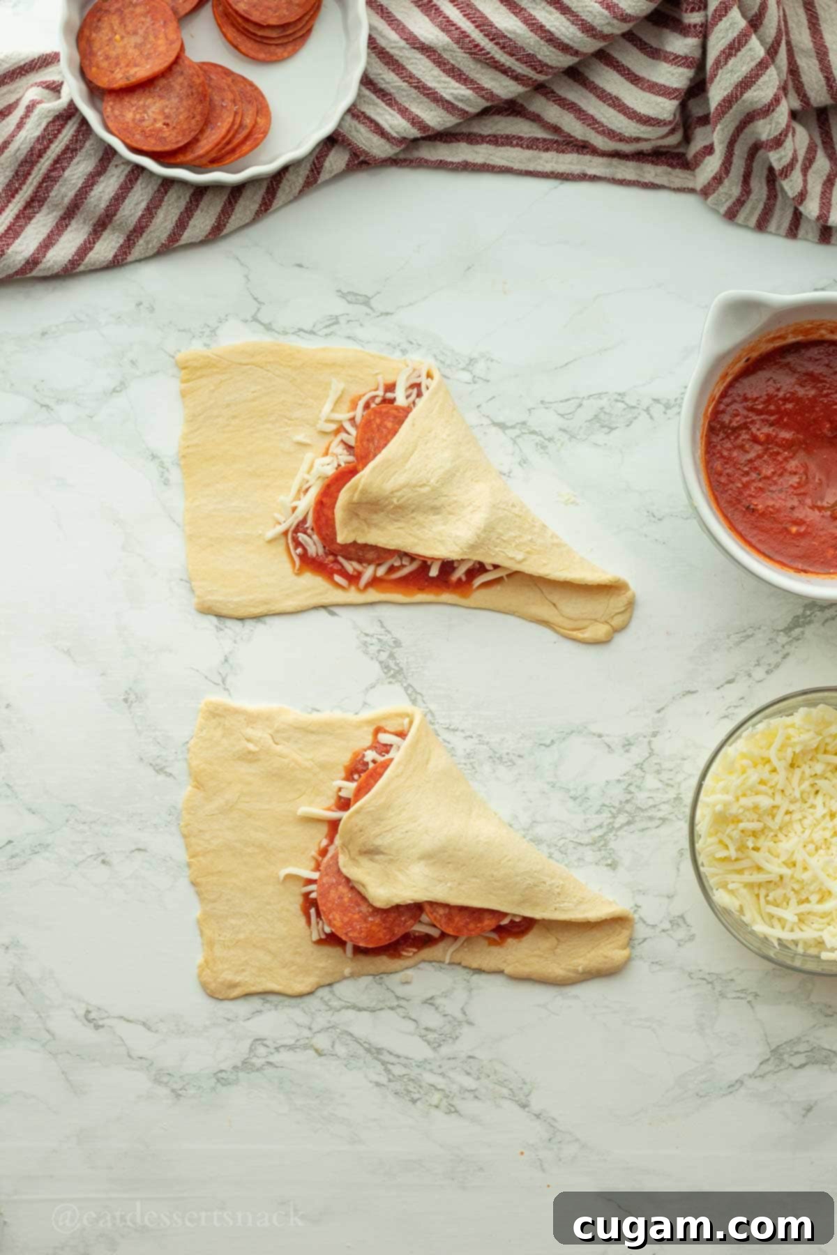 Halloween Witchy Crescent Treats 8 Folded raw crescent dough over pizza sauce and cheese.
