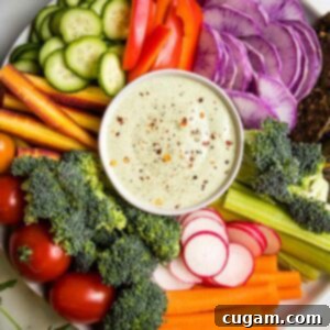 Vegan ranch in a small bowl in the center of the photo, surrounded by colorful cut-up veggies ready for dipping.