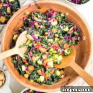 wooden salad bowl filled with colorful chopped salad: tuscan kale, purple carrots, red peppers, purple cabbage, cucumbers and marcona almonds