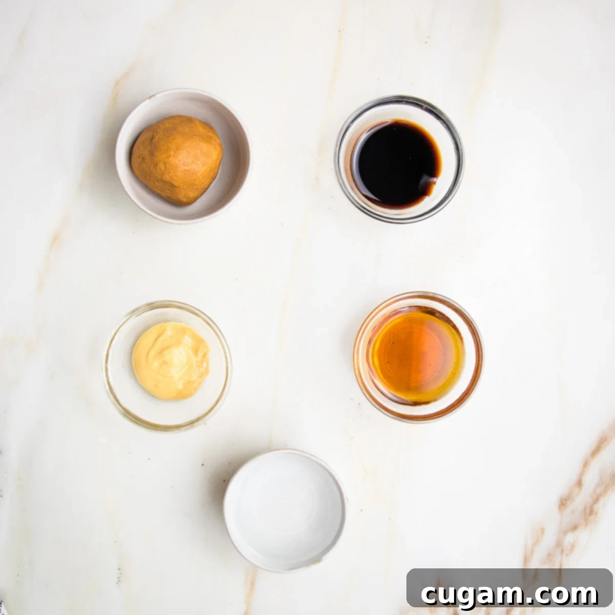 Small bowls filled with light miso, balsamic vinegar, dijon mustard, maple syrup and water.