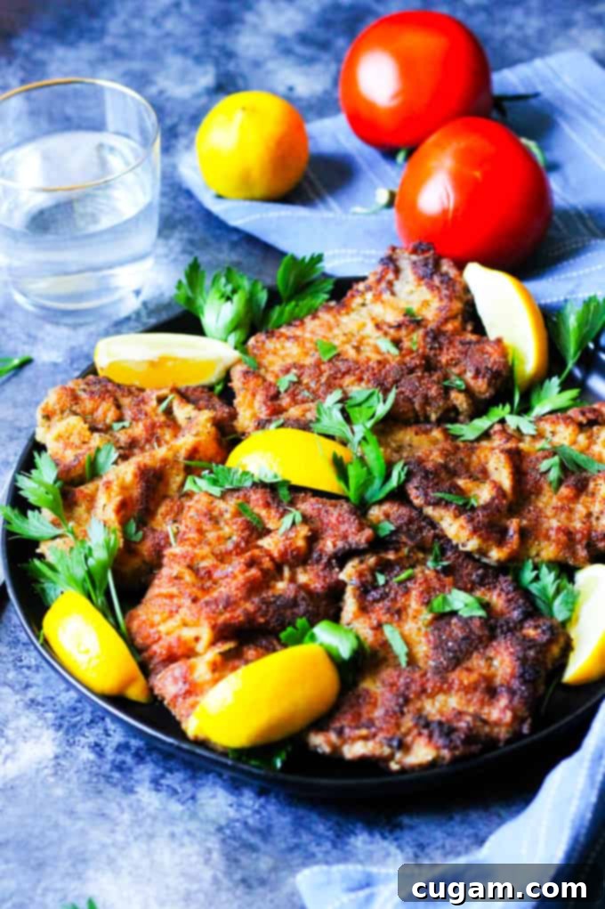 Veal Milanese on a plate with lemon wedges