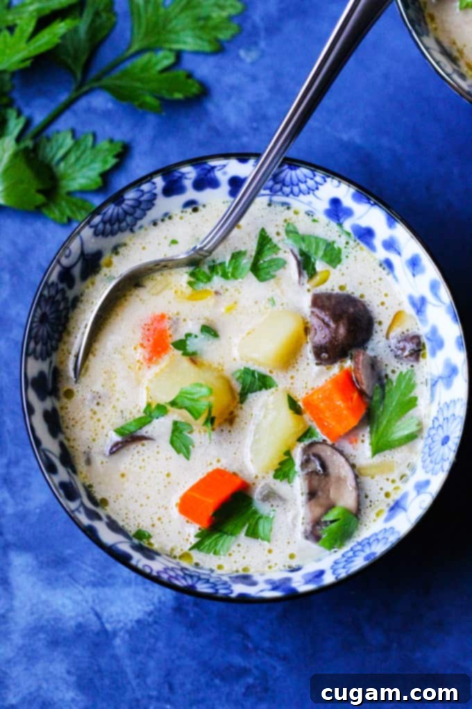 Hearty Polish Mushroom soup served in a blue bowl with a silver spoon, garnished with fresh parsley.