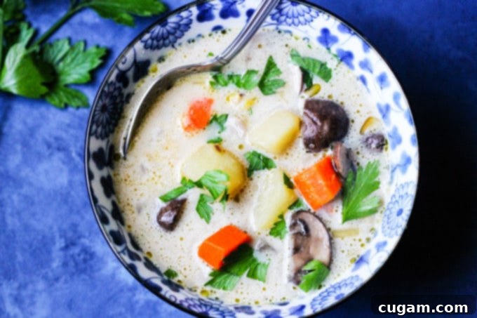 A close-up shot of homemade chunky mushroom soup in a deep blue bowl, garnished with fresh herbs.