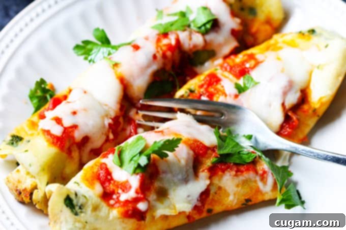 Savory crepes on a plate with a fork cutting into one, showing the chicken and cheese filling
