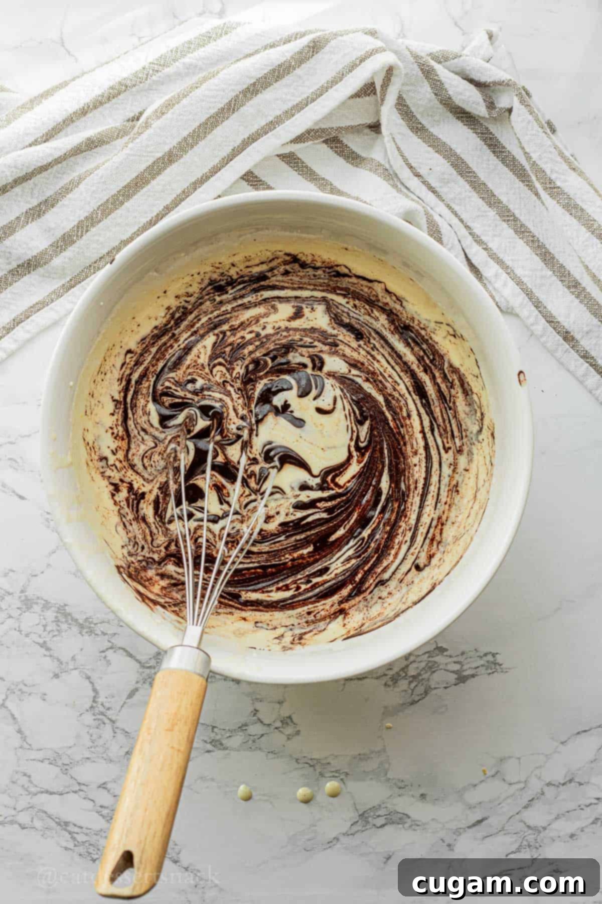 The rich butter and cocoa powder mixture being poured into the fluffy wet ingredients (eggs, sugar, sourdough discard, vanilla) in a white mixing bowl, ready to be combined.