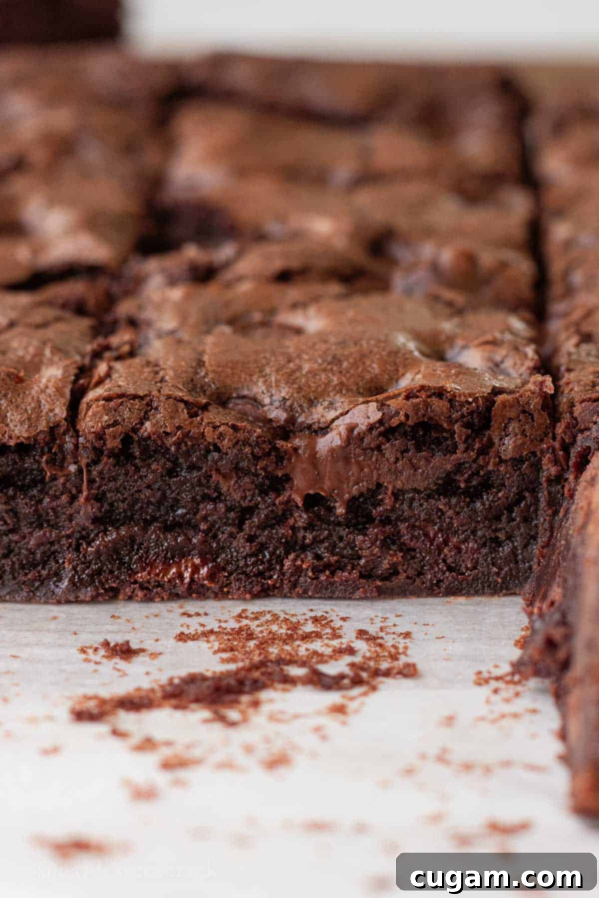 A single slice of baked sourdough brownie with a visible crackly top and fudgy interior, resting on parchment paper, ready to be enjoyed.