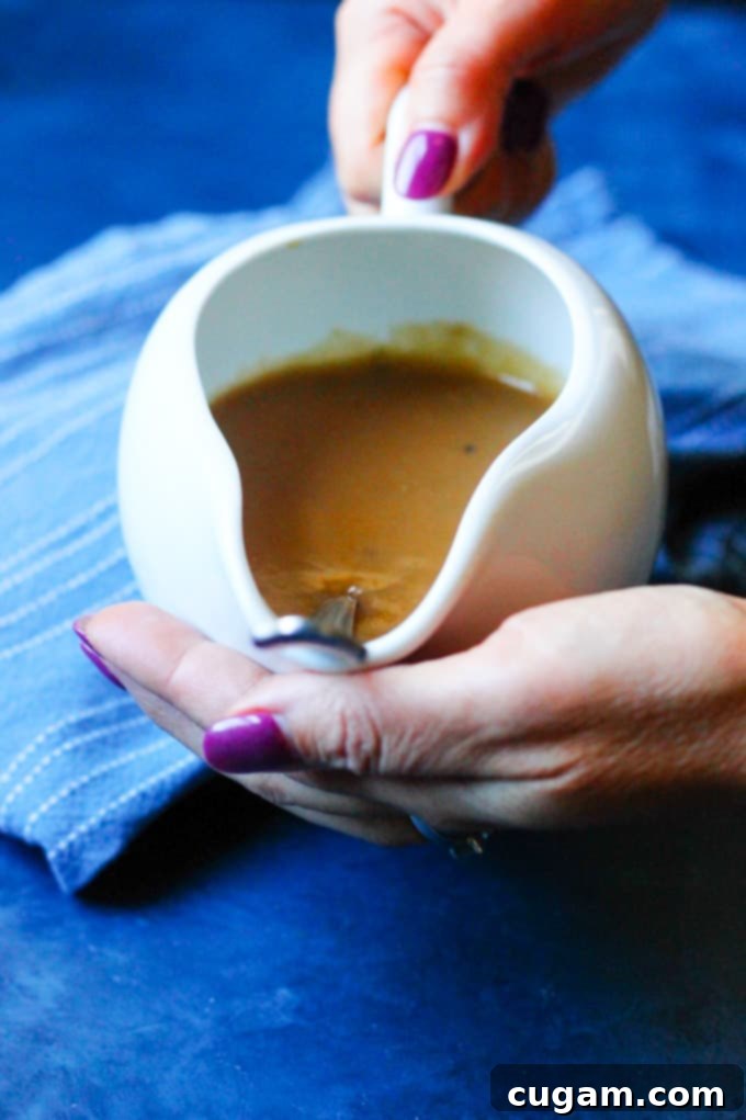 Hands holding a serving dish filled with rich, easy homemade gravy and a spoon
