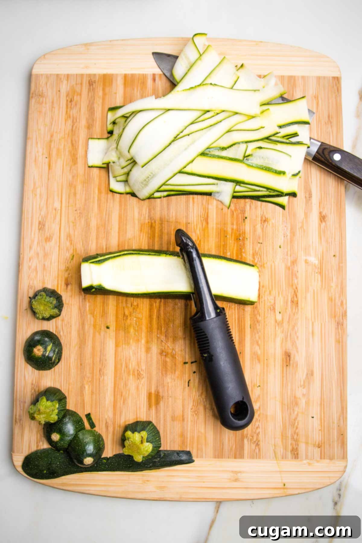Preparing long strips of zucchini for lasagna roll ups. A vegetable peeler makes long thin strips when pulled across the length of a zucchini after it's been trimmed.
