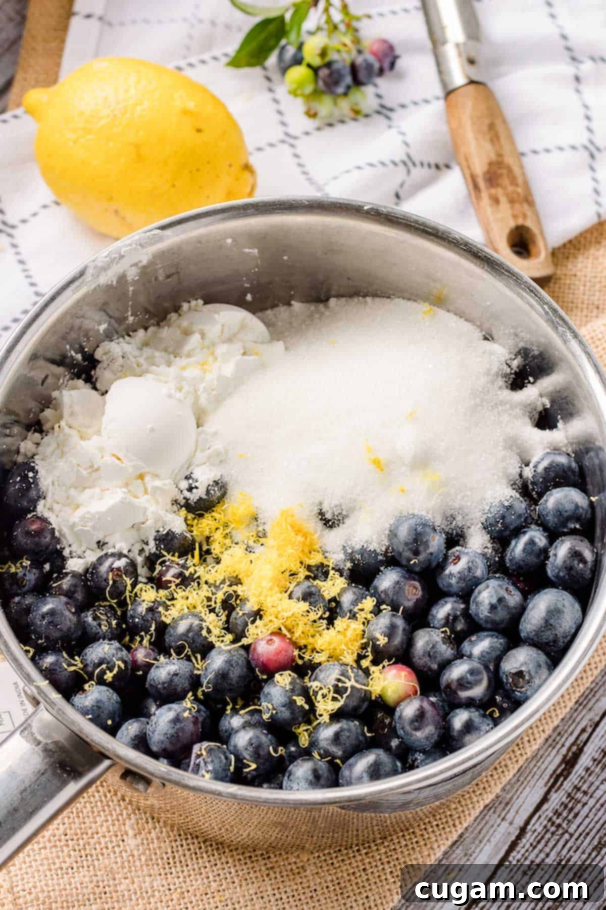 Raw blueberries, sugar, cornstarch, lemon zest in a metal pan.