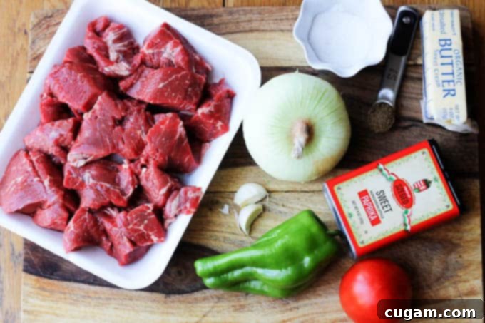 Ingredients needed to make Hungarian beef stew, including onions, beef, paprika, and peppers