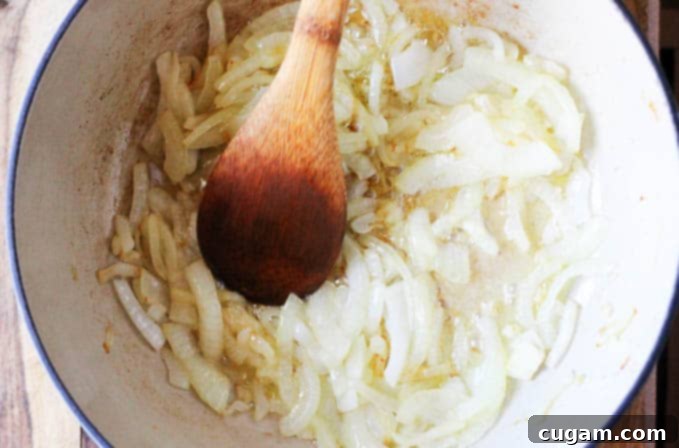 Sautéing thinly sliced onions in a pot for Pörkölt