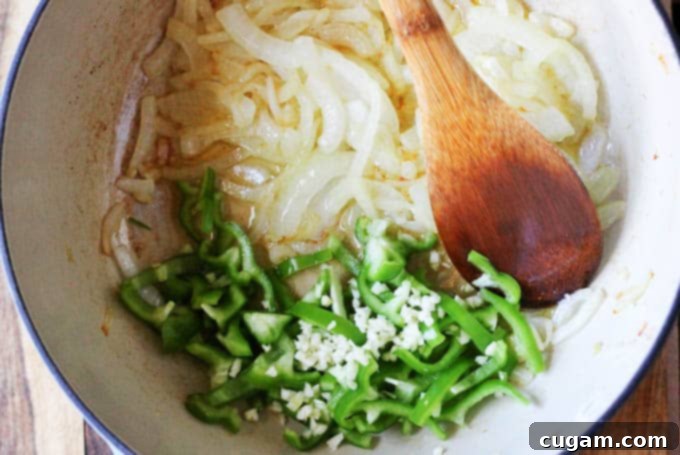 Adding garlic and sliced green pepper to sautéed onions