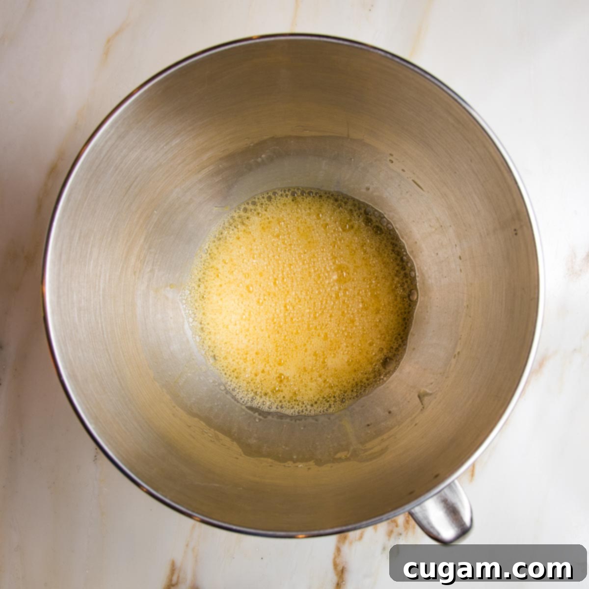 Wet ingredients for lemon cake: frothy eggs, olive oil, honey and lemon juice.