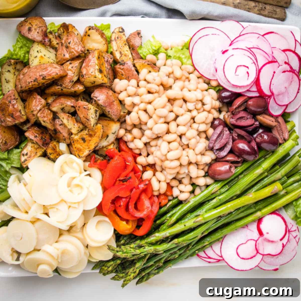 Composed nicoise salad with potatoes, hearts of palm, red peppers, asparagus, radish, small white beans and olives.