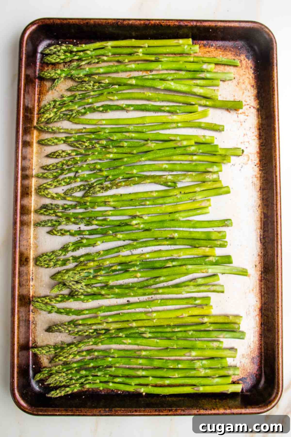 Fresh asparagus spears on a rimmed baking sheet already roasted in the oven.