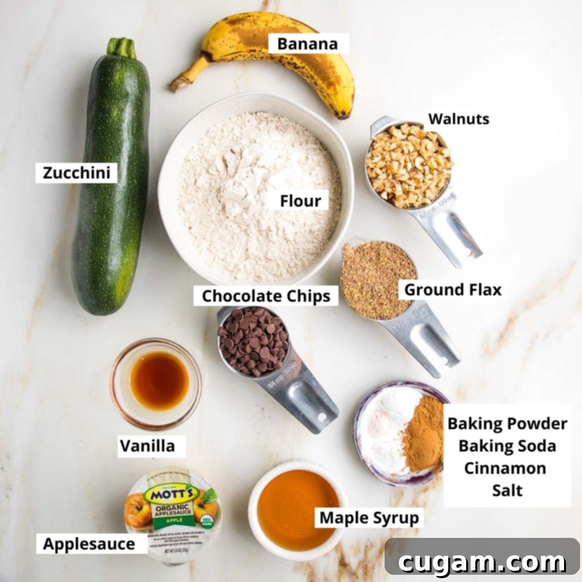 Vegan Zucchini Muffins 3 Labeled zucchini muffin ingredients: banana, zucchini, flour, walnuts, flaxseed, chocolate chips, vanilla, maple syrup, baking soda, baking powder, cinnamon, showcasing the natural components of these healthy muffins.