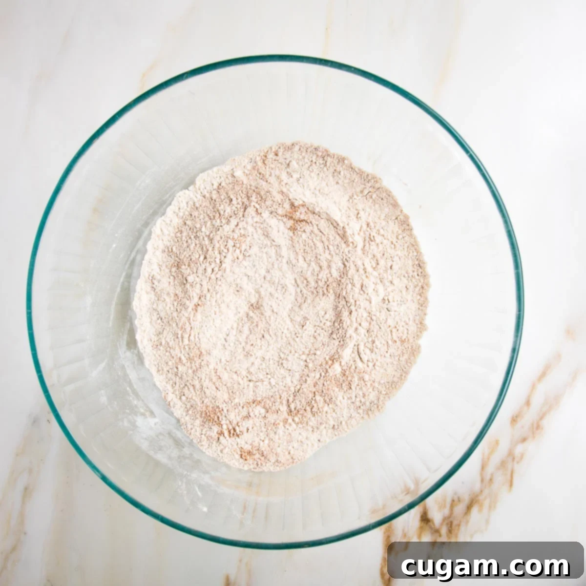 Vegan Zucchini Muffins 8 Dry ingredients for muffins mixed together in a glass bowl, showcasing their fine, uniform consistency.