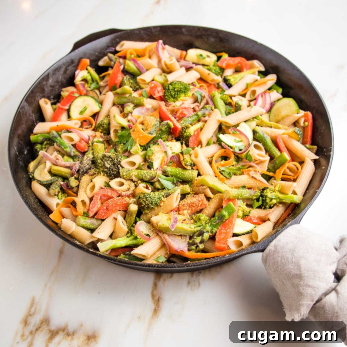 Cast iron skillet filled with colorful pasta and fresh veggies. 